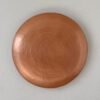 Lámpara en forma de disco de cobre martillado con textura circular, similar a un eclipse.