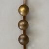 Lámpara Orion: tres esferas doradas martilladas en una tabla de madera.